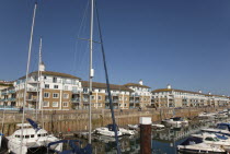 England, East Sussex, Brighton, view over boats moored in the Marina with apartment buildings behind.