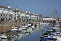 England, East Sussex, Brighton, view over boats moored in the Marina with apartment buildings behind.