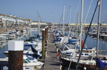 England, East Sussex, Brighton, view over boats moored in the Marina with apartment buildings behind.