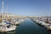 England, East Sussex, Brighton, view over boats moored in the Marina with apartment buildings behind.