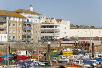 England, East Sussex, Brighton, view over fishing boats moored in the Marina with apartment buildings behind.