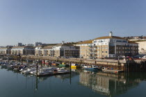 England, East Sussex, Brighton, view over boats moored in the Marina with apartment buildings behind.