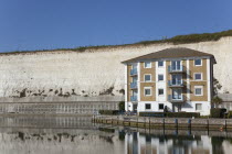 England, East Sussex, Brighton, apartment building in empty marina with chalk cliffs behind.