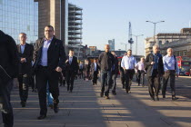 England, London, Early morning commuters crossing London Bridge towards the City Financial district.