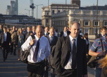 England, London, Early morning commuters crossing London Bridge towards the City Financial district.