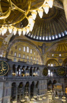 Turkey, Istanbul, Sultanahmet, Haghia Sophia Sighseeing tourists beneath the dome with murals and chandeliers in the Nave of the Cathedral.