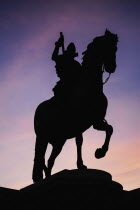 Spain, Madrid, Statue of King Philip II in Plaza Mayor silhouetted against evening sky.