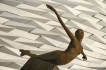 Ireland, Belfast, Titanic Quarter, Titanic Belfast Visitor Experience, 'Titanica' sculpture by Rowan Gillespie with section of the building in the background.