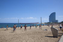 Spain, Catalonia, Barcelona, Playa de St Sebastia, Barceloneta Beach, people playing volleyball with the W hotel behind.