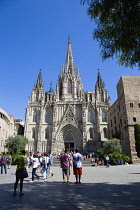 Spain, Catalonia, Barcelona, People in the street and on the steps below the main facade of the Gothic Cathedral in the Old Town district.