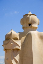 Spain, Catalonia, Barcelona, Chimneys and vents on the roof of Casa Mila apartment building known as La Pedrera or Stone Quarry designed by Antoni Gaudi in the Eixample district.