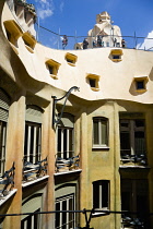 Spain, Catalonia, Barcelona, Tourist visitors on the roof of Casa Mila apartment building known as La Pedrera or Stone Quarry designed by Antoni Gaudi in the Eixample district.