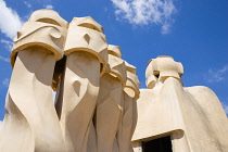 Spain, Catalonia, Barcelona, Chimneys and vents on the roof of Casa Mila apartment building known as La Pedrera or Stone Quarry designed by Antoni Gaudi in the Eixample district.