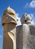 Spain, Catalonia, Barcelona, Chimneys and vents on the roof of Casa Mila apartment building known as La Pedrera or Stone Quarry designed by Antoni Gaudi in the Eixample district.