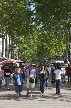 Spain, Catalonia, Barcelona, Tourist walking along the tree lined avenue of La Rambla.