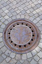 Germany, Berlin, Mitte, Museum Island, Ornately cast manhole cover showing local landmarks.