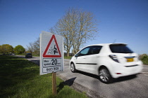 Transport, Road, Cars, resurfaced road with sign warning of reduced speed limit and loose chippings.