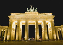 Germany, Berlin, Mitte, Brandenburg Gate or Bransenburger Tor in Pariser Platz illuminated at night leading to Unter den Linden and the Royal Palaces with the Quadriga of Victory on top. The only rema...