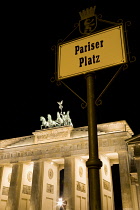 Germany, Berlin, Mitte, Brandenburg Gate or Bransenburger Tor and roadsign for Pariser Platz illuminated at night leading to Unter den Linden and the Royal Palaces with the Quadriga of Victory on top....