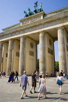 Germany, Berlin, Mitte, sightseeing tourists at the Brandenburg Gate or Bransenburger Tor in Pariser Platz leading to Unter den Linden and the Royal Palaces with the Quadriga of Victory on top. The on...