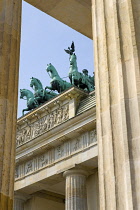 Germany, Berlin, Mitte, Brandenburg Gate or Bransenburger Tor seen between columns in Pariser Platz leading to Unter den Linden and the Royal Palaces with the Quadriga of Victory on top. The only rema...