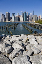 USA, New York, Lower Manhattan skyline skyscrapers seen from Brooklyn Bridge Park with wooden piles of Pier One in the East River.