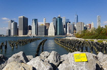 USA, New York, Lower Manhattan skyline skyscrapers seen from Brooklyn Bridge Park with wooden piles of Pier One in the East River.