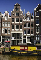 Netherlands, Noord Holland, Amsterdam, typical canal scene along the Herengracht with tall houses and boat sitting on the canal.