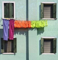 Italy, Veneto, Burano Island, Colourful washing hanging on house facade.