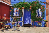 Italy, Veneto, Burano Island, Colourful facade with floral display around the doorway.