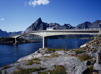 Norway, Lofotens, Moskenesoya, Bridge linking the villages of Reine and Hamnoy with two buses crossing and Mt. Olstinden  675 metres in backgound.