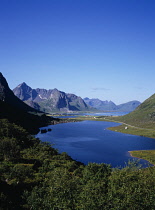 Norway, Lofoten, Storvatnet Lake, View across lake west of the village of Napp with Flakstadtinden mountain behind with single cloud drifting across peak.