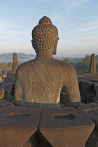 Indonesia, Java, Borobudur, Rear view of a seated Buddha in the warm, early-morning sun