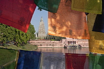 India, Bihar, Bodhgaya, Mahabodhi Temple framed by colourful Buddhist prayer flags.