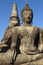 Thailand, Sukothai, Seated Buddha with a large, brick stupa in the background, Wat Mahathat Royal Temple.