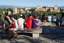 Spain, Andalucia, Granada, Tourists look across to the Alhambra from the viewpoint at Iglesia de San Nicolas in the Albayzin district.