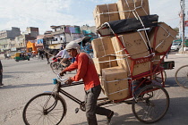 India, Delhi, A man hauls a bicycle laden with goods through the streets of Delhi.