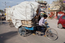 India, Delhi, A man hauls a bicycle laden with goods through the streets of Delhi.