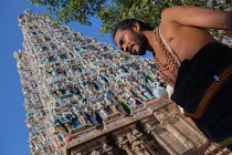 India, Tamil Nadu, Madurai, Pilgrim in front of the west tower gopuram of the Sri Meenakshi Temple in Madurai.