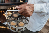 India, Maharashtra, Dhule, Man carrying a holder filled with glasses of chai.