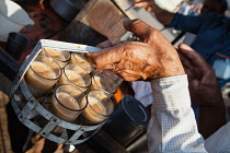 India, Maharashtra, Dhule, Man carrying a holder filled with glasses of chai.