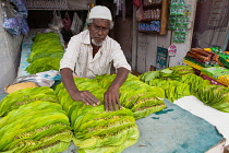 India, Tamil Nadu, Kumbakonam, A muslim man arranges a display of betel leaves at his stall in the market at Kumbakonam.