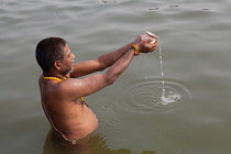 India, Uttar Pradesh, Varanasi, A pilgrim praying in the River Ganges.