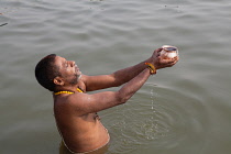 India, Uttar Pradesh, Varanasi, A pilgrim praying in the River Ganges.