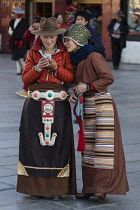 Two young Khamba Tibetan women from the Kham region of eastern Tibet on a pilgrimage to visit holy sites in Lhasa, Tibet.  One is wearing a western-style felt hat, which is very popular in the Kham re...