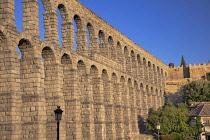 Spain, Castile and Leon, Segovia, Early morning golden light on the Aqueduct of Segovia, a Roman aqueduct with 167 arches built around the first century AD to channel water from springs in the mountai...