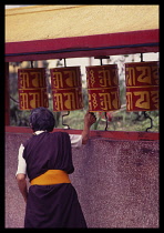 India, Sikkim, Gangtok, Woman turning prayer wheels at Buddhist monastery.