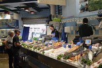 France, Pays Basque, St Jean de Luz, Female fishmonger weighing fish for customers in the Fish market.