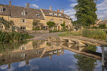 England, Gloucestershire, Cotswolds, Lower Slaughter, River Eye and typical golden Cotswold streetscape in evening light.