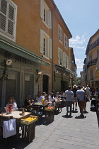 France, Provence-Alpes-Cote d'Azur, Antibes, Narrow street in the Old town with eople sat outside restaurants.